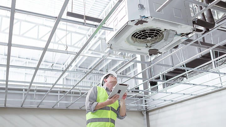 Man in safety gear inspects an industrial air vent