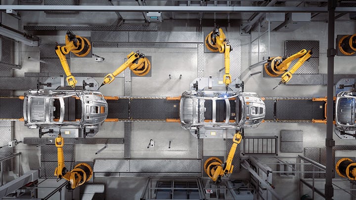 Automotive assembly line showing car frames being welded by robotic arms