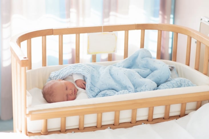 Newborn baby in hospital room. New born child in wooden co-sleeper crib.