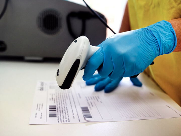 nurse in blue latex gloves scanning barcode on a piece of paper
