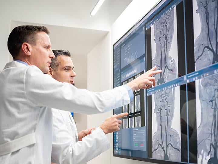 Two radiologists looking at images of an MRI on a medical lightbox