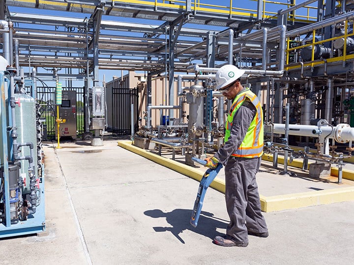 Subsurface Utility Mapping with person in a hardhat and yellow caution vest using a mapping device in an industrial area