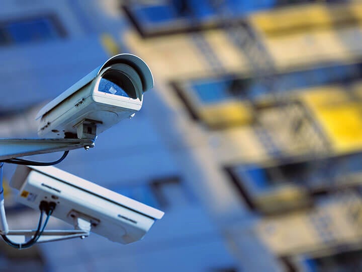 close up of two security cameras monitoring the street in the city