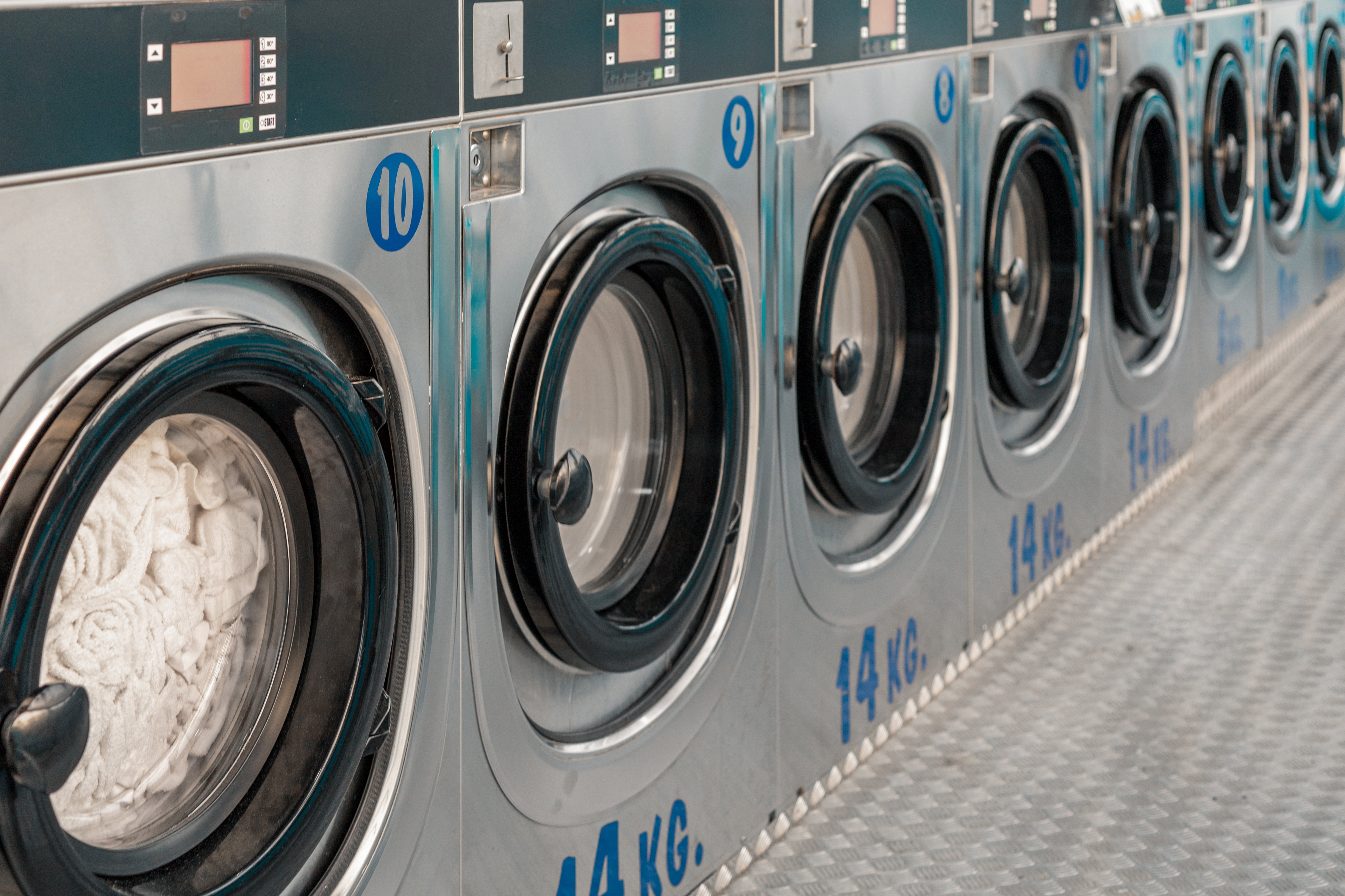 Row of washing machines in public laundry. Commercial cleaning services or utility management in communal spaces. Laundromat. Shared amenities. Self-service, coin laundry, or coin wash.