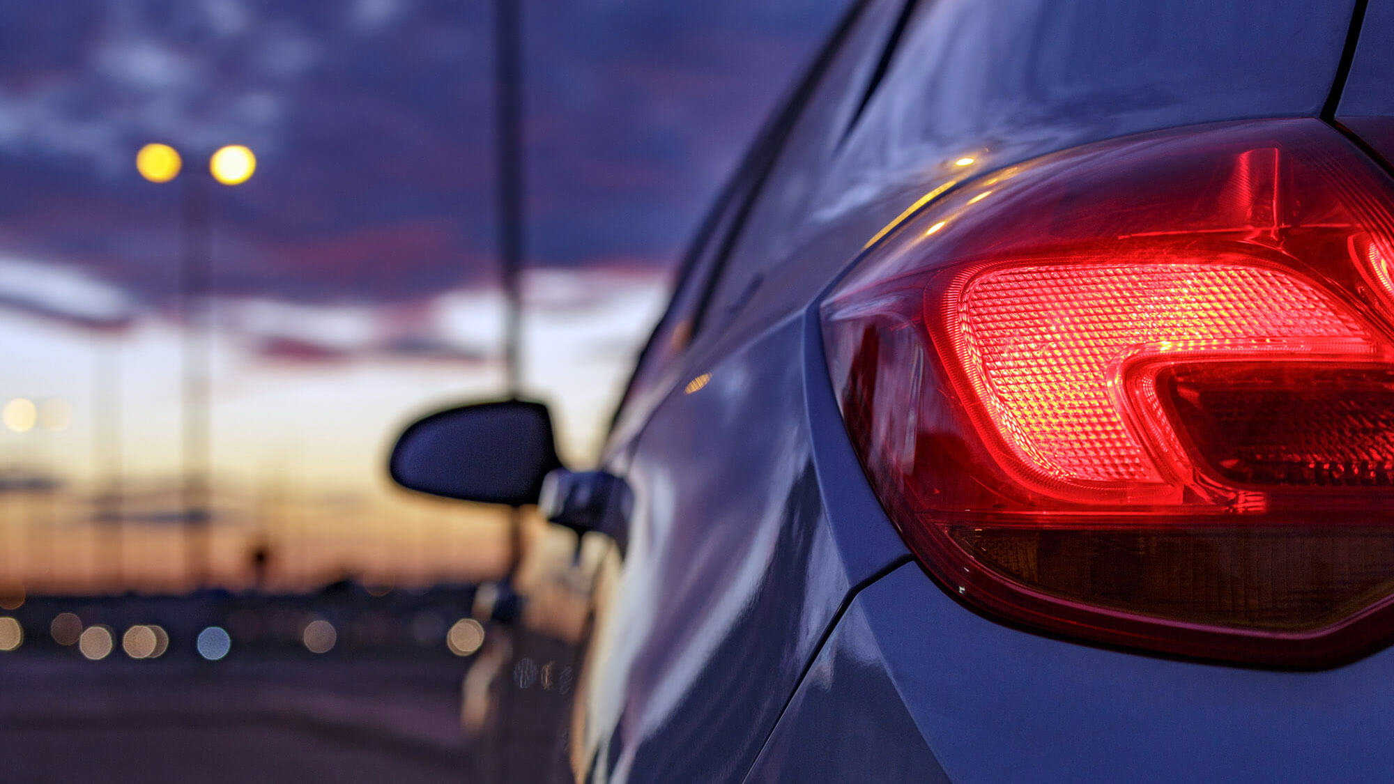 Rear headlight car against defocused background of traffic lights at dusk